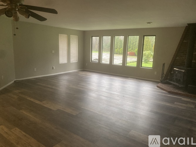 A spacious room with wooden flooring and a ceiling fan.