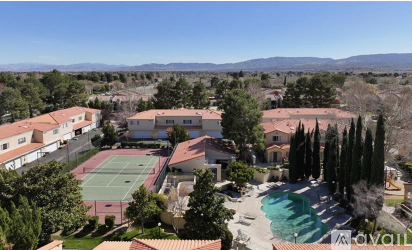 A tennis court is surrounded by houses and trees.