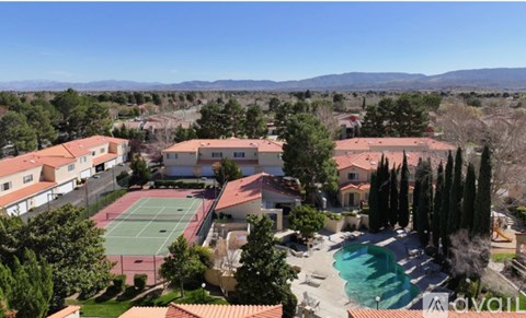 A tennis court is surrounded by houses and trees.