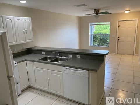 A kitchen with white cabinets and a black countertop.