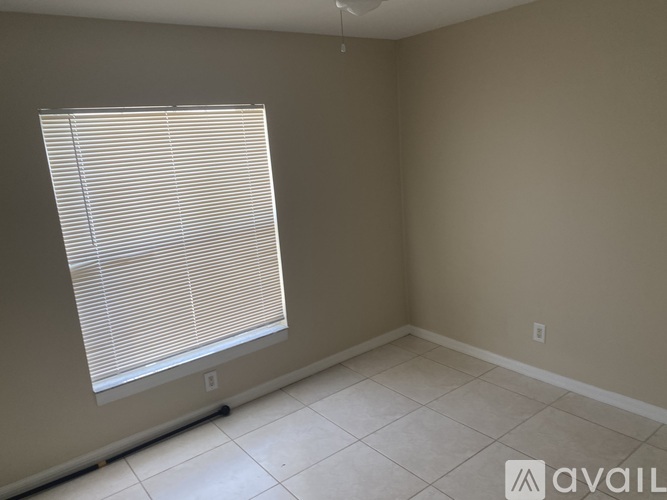 A room with a window covered in blinds and a tiled floor.