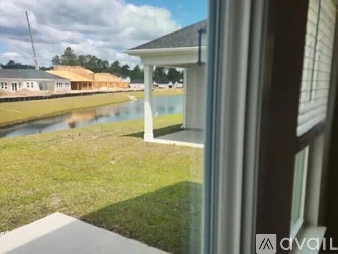 A view from a window looking out to a grassy area and a building.