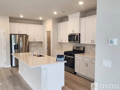 A kitchen with white cabinets and a stainless steel refrigerator.