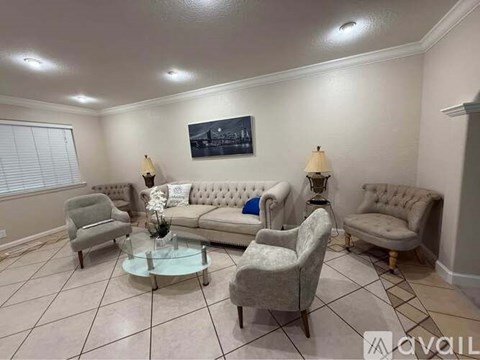 A living room with a grey sofa, two armchairs, a coffee table, and a painting on the wall.