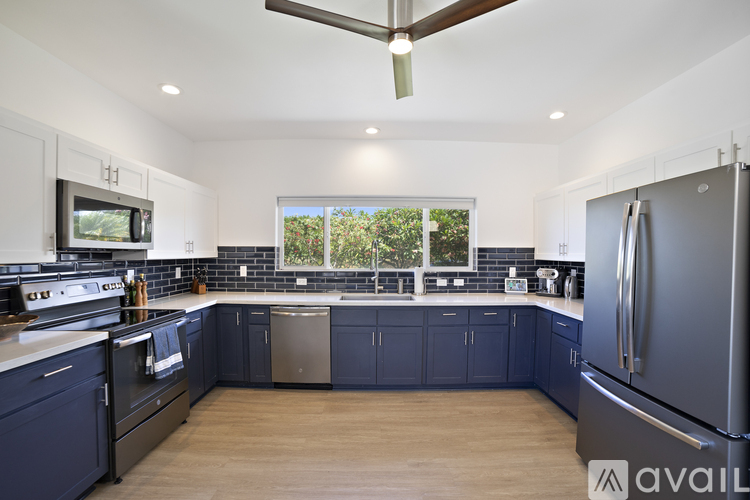 A kitchen with dark blue cabinets and a stainless steel refrigerator.