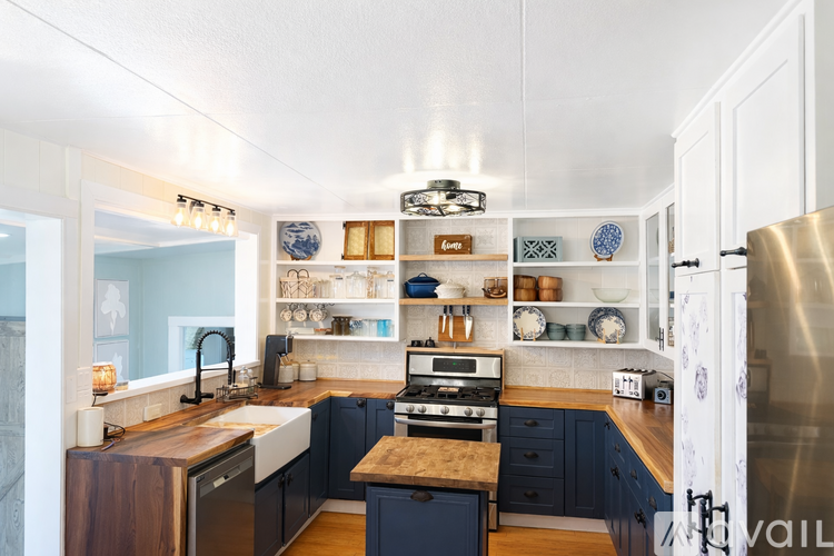 A modern kitchen with dark blue cabinets and a wooden island.