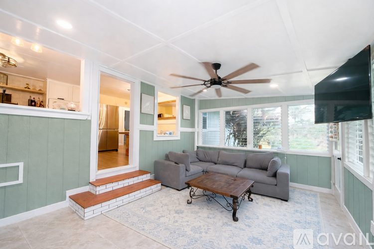 A living room with a grey couch and a ceiling fan.