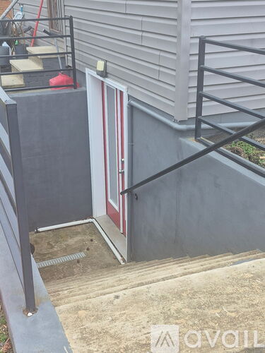A red door is on the left side of a concrete staircase.