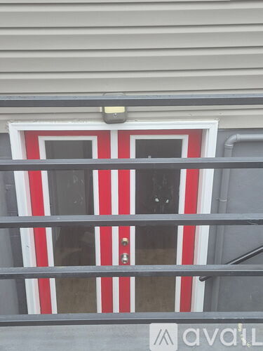A red and white striped door with a metal railing in front.