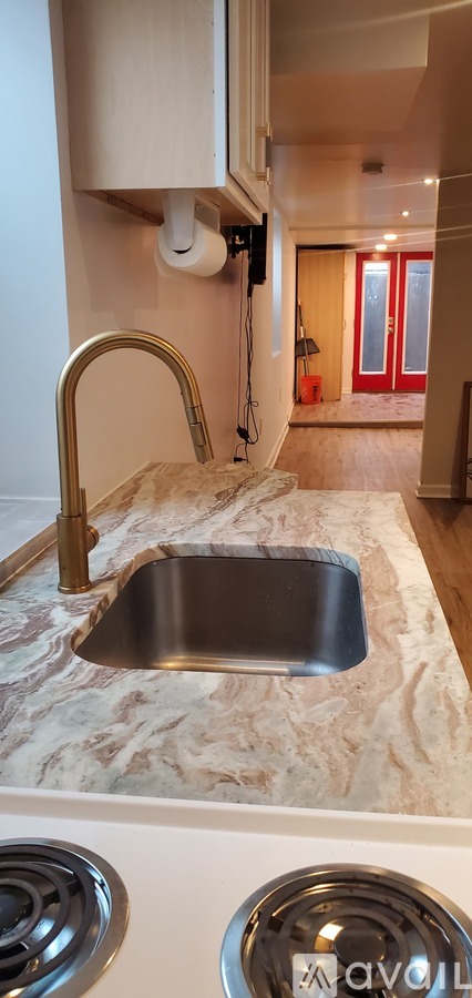 A kitchen with a marble countertop and a stainless steel sink.