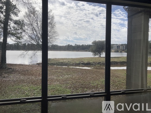 A view of a lake through a window with a tree on the left and a building on the right.