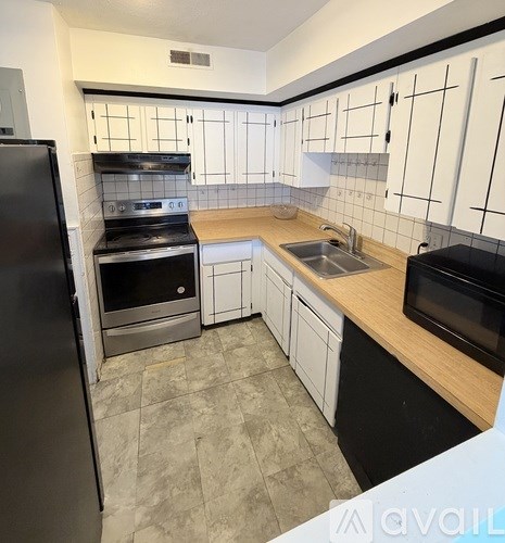 A kitchen with black appliances and white cabinets.