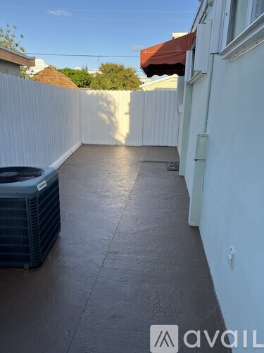 A patio with a wall and a heat pump.