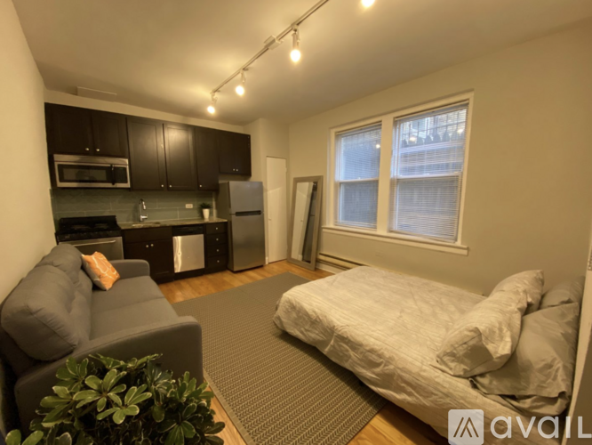 A small room with a bed, couch, and kitchenette.