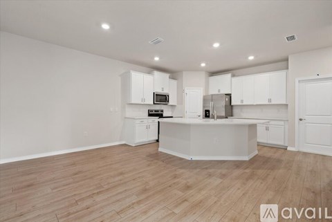 A kitchen with white cabinets and a wooden floor.