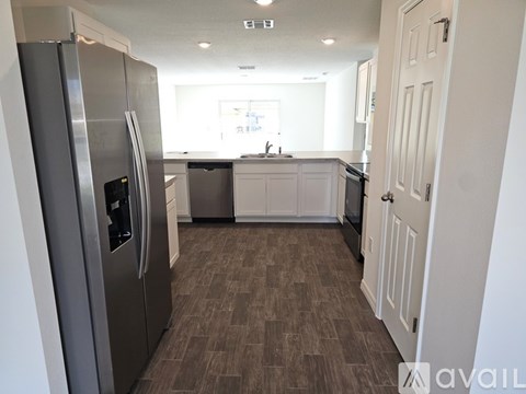 A kitchen with a refrigerator on the left and a sink in the middle.