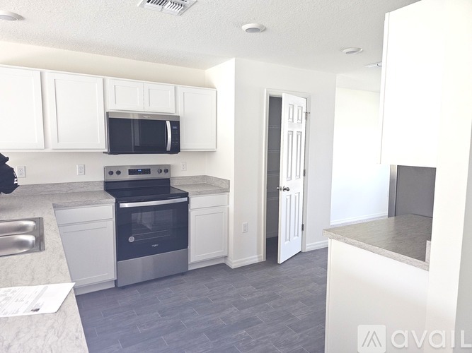 A kitchen with white cabinets and a black microwave above the stove.