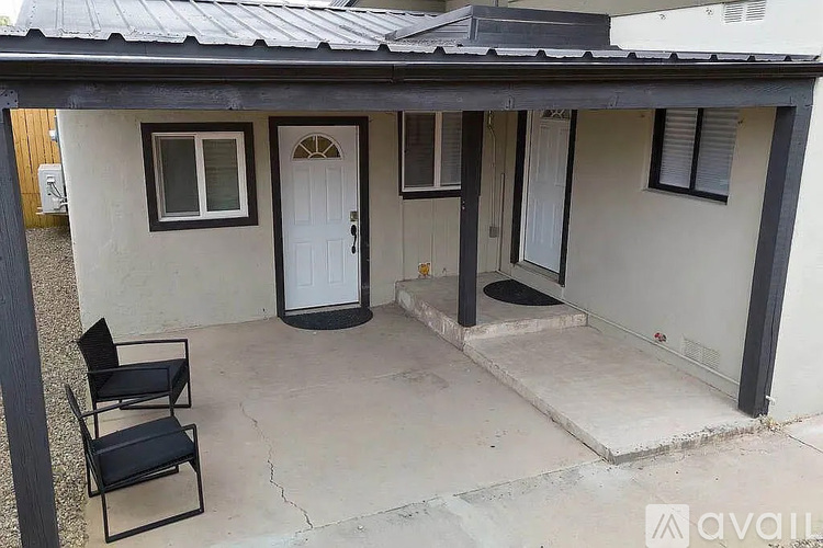 A small house with a white door and a black chair in front.
