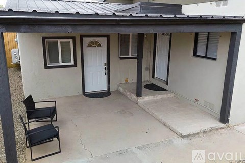 A small house with a white door and a black chair in front.