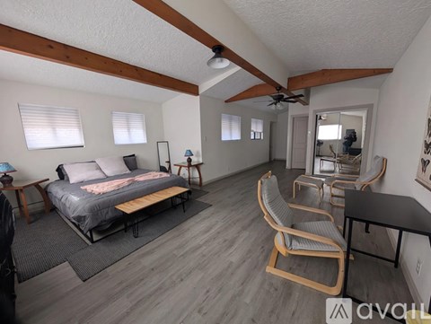 A bedroom with a bed, chair, and a ceiling fan.