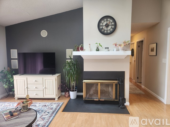 A living room with a fireplace, a clock, and a rug.