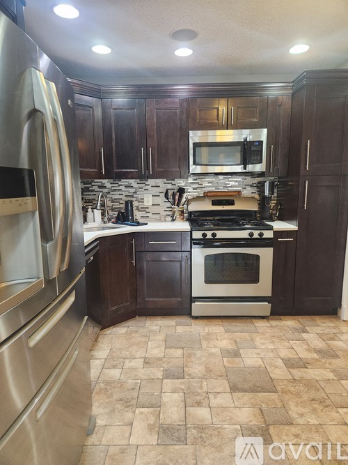 A kitchen with dark wood cabinets and a tiled floor.
