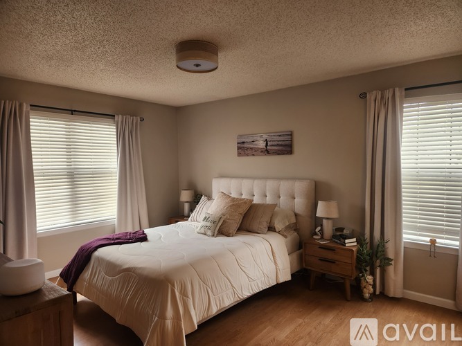 A well-lit bedroom with a large bed and a painting on the wall.