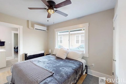 A bedroom with a bed, a ceiling fan, and a window.