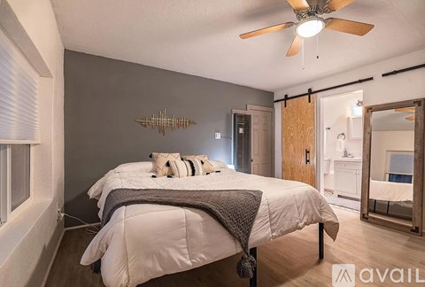 A bedroom with a bed, a ceiling fan, and a mirror.