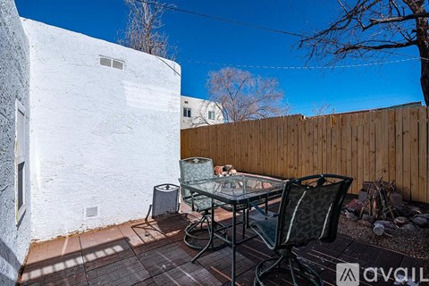 A patio with a table and chairs is set up outside a white building.