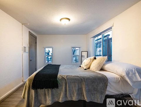 A bedroom with a bed covered in a grey blanket and two pillows.