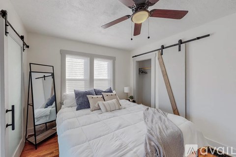 A bedroom with a white bed and a ceiling fan.