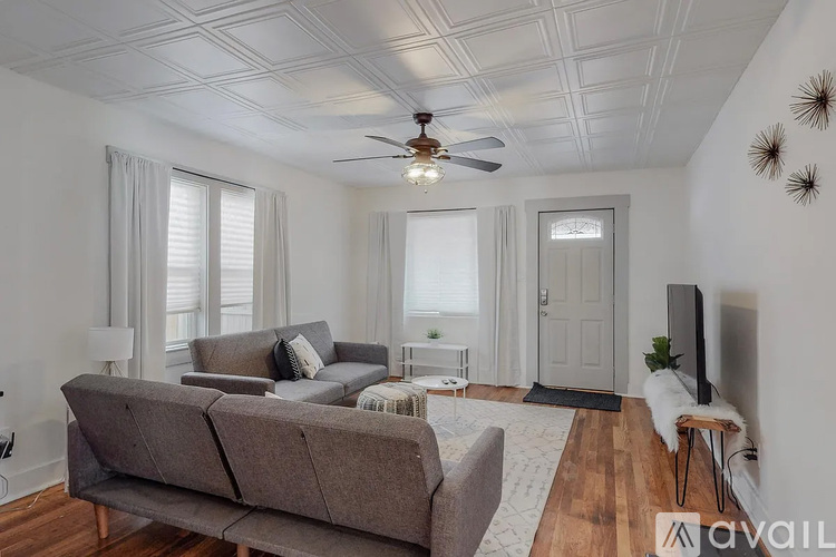 A living room with a grey couch and a ceiling fan.