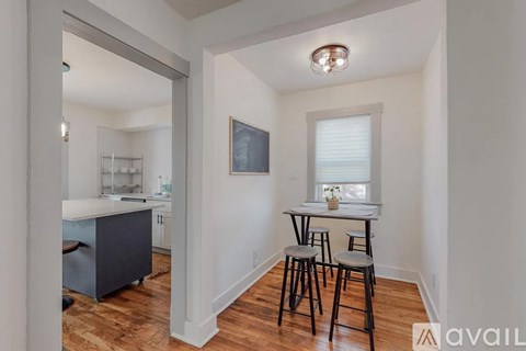 A kitchen with a table and chairs in the foreground and a fridge in the background.