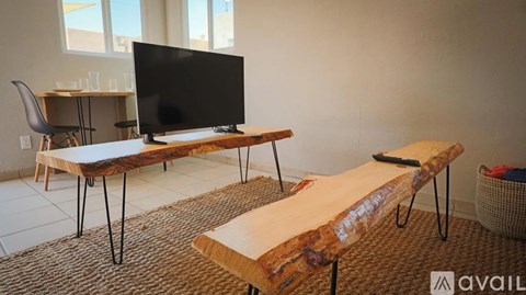 A black television is on a wooden stand in a room with a carpet.