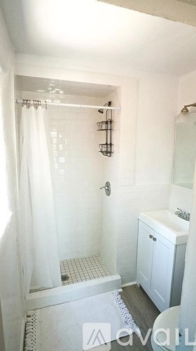 A white bathroom with a shower curtain and a white cabinet.