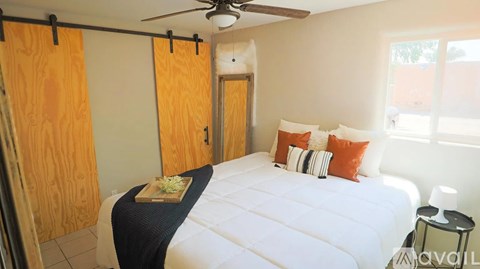 A bedroom with a bed, pillows, and a ceiling fan.
