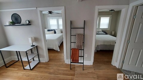 A bedroom with a bed, a chair, and a mirror.
