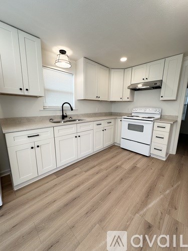 A kitchen with white cabinets and a wooden floor.