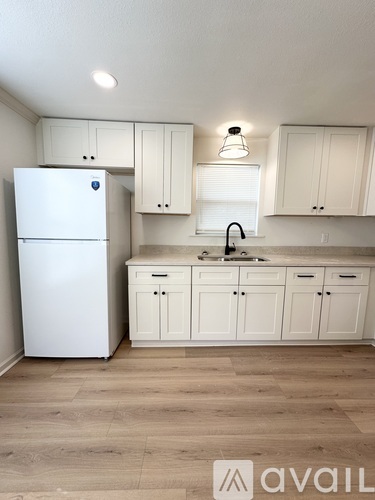 A kitchen with white cabinets and a white fridge.