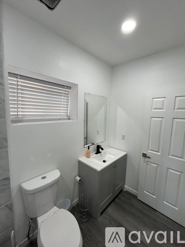 A bathroom with a toilet, sink, and mirror.