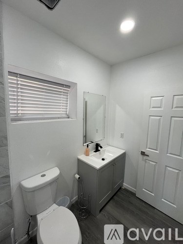 A bathroom with a toilet, sink, and mirror.