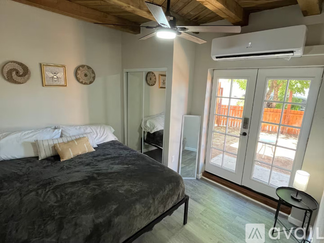 A bedroom with a bed, a ceiling fan, and a sliding glass door.