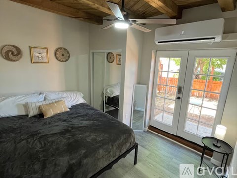 A bedroom with a bed, a ceiling fan, and a sliding glass door.