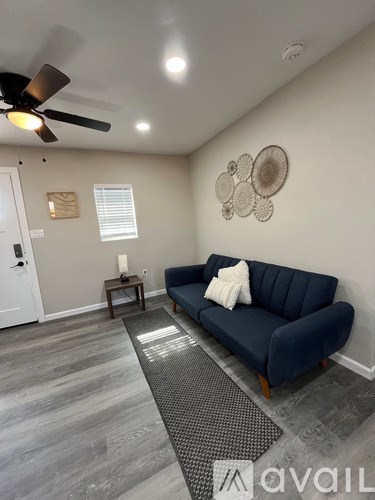 A living room with a blue couch and a ceiling fan.