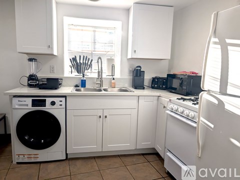 A kitchen with white appliances and cabinets.