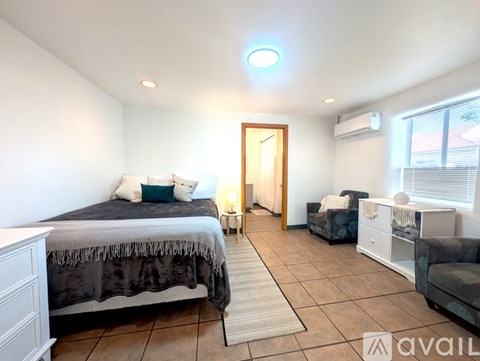 A bedroom with a bed, couch, and a rug.