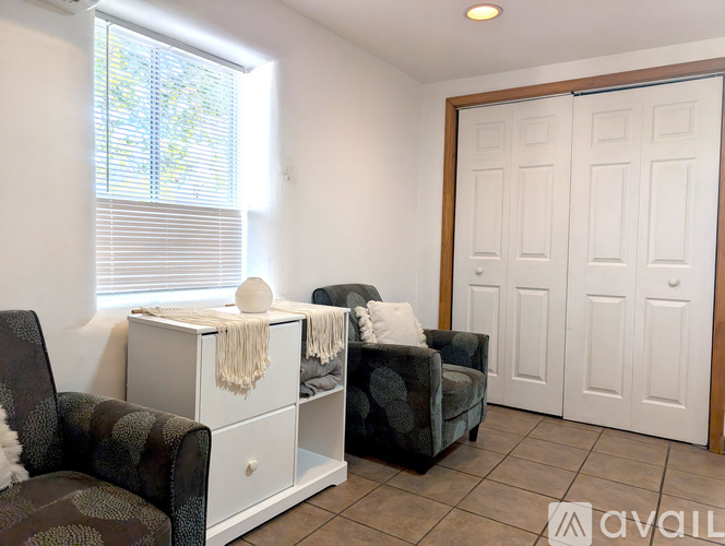 A living room with a brown chair, a white cabinet, and a black couch.