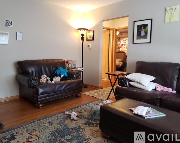 A living room with a brown leather couch and a rug on the floor.