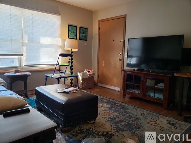 A living room with a television, a chair, a table, and a rug.